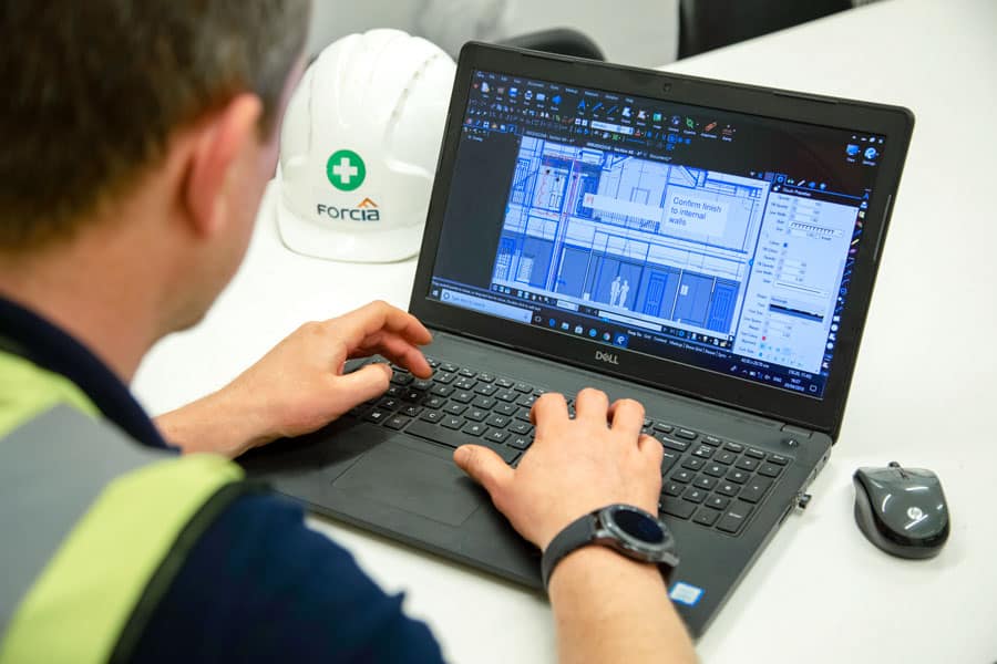 man working on laptop with digital construction drawings