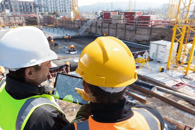 Two construction workers with a tablet survey a jobsite